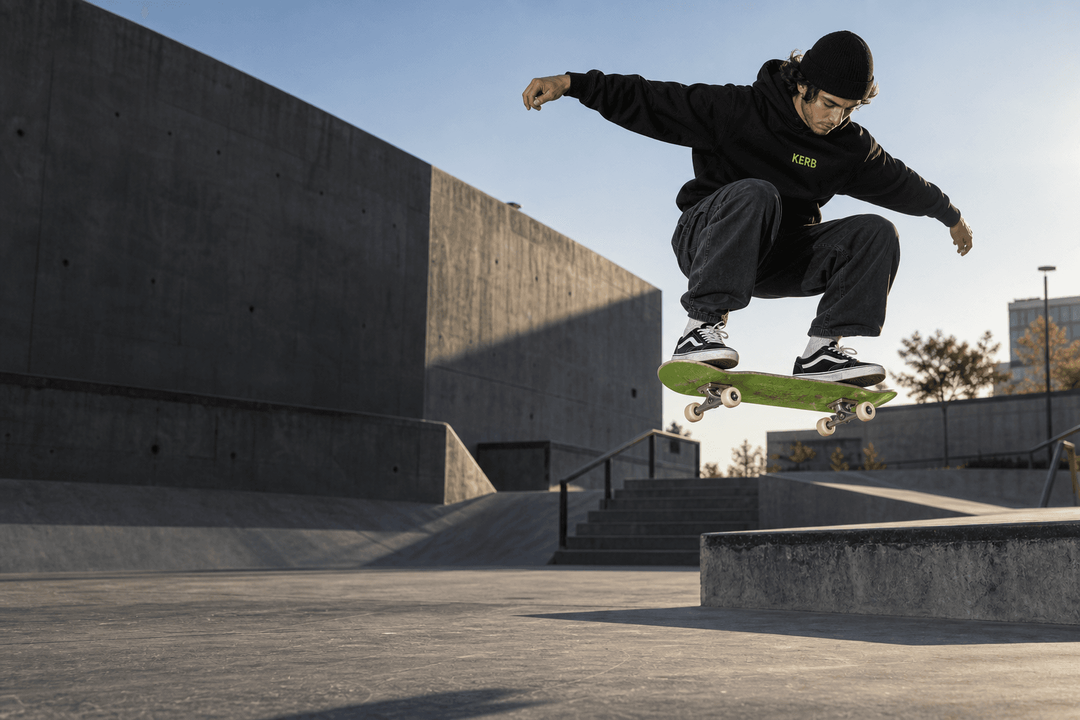 A skater in a KERB hoodie ollies an acid-green skateboard above a concrete skatepark.